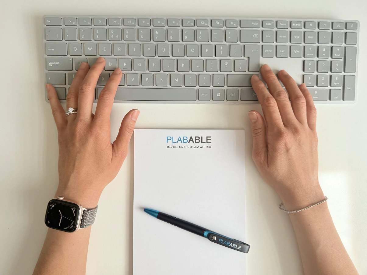 Plabable branded notepad and pen on a marble surface